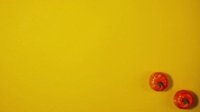 Halloween background with moving plastic decorative pumpkins on a yellow background. copyspace. Stop motion animation