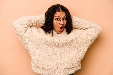 Young African American woman isolated on beige background screaming, very excited, passionate, satisfied with something.