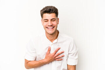 Young caucasian man isolated on white background laughs out loudly keeping hand on chest.