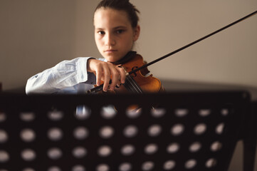 Teenager playing violin indoors. Teenage violinist student practicing at school, selective focus on...