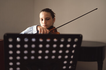 Teenager playing violin indoors. Teenage violinist student practicing at school.