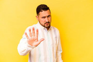 Young hispanic man isolated on yellow background rejecting someone showing a gesture of disgust.