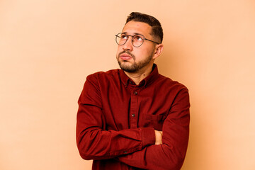 Young hispanic man isolated on beige background tired of a repetitive task.