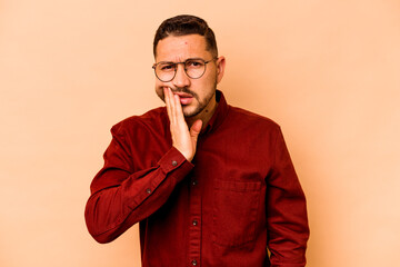 Young hispanic man isolated on beige background having a strong teeth pain, molar ache.