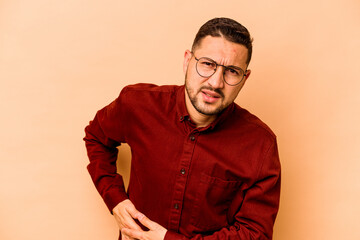 Fototapeta premium Young hispanic man isolated on beige background having a liver pain, stomach ache.