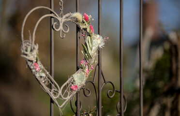 Herz aus Metall als Dekoration mit Blumenschmuck an einem Metallzaun antik als Zeichen der Liebe...