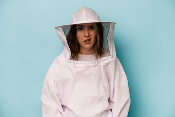 Young caucasian beekeeper woman isolated on blue background showing a disappointment gesture with...