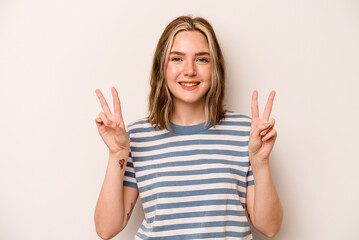 Young caucasian woman isolated on white background showing victory sign and smiling broadly.