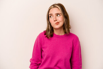 Young caucasian woman isolated on white background shrugs shoulders and open eyes confused.