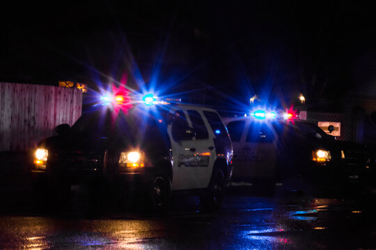 Police cruisers vehicles with flashing lights at vehicle accident on cold wet dark night