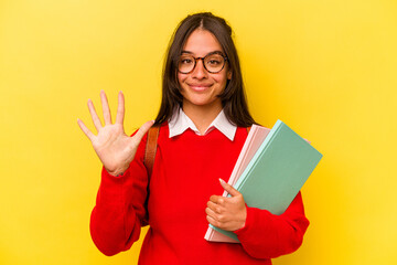 Young student hispanic woman isolated on yellow background smiling cheerful showing number five with fingers.