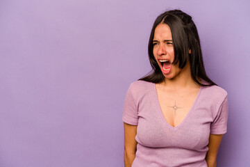 Young hispanic woman isolated on purple background shouting very angry, rage concept, frustrated.