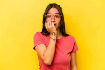Young hispanic woman isolated on yellow background biting fingernails, nervous and very anxious.