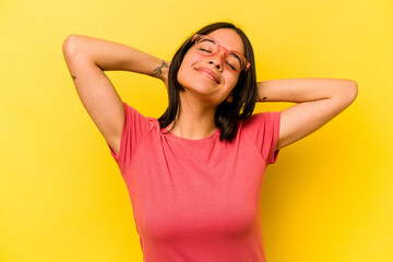Fototapeta premium Young hispanic woman isolated on yellow background feeling confident, with hands behind the head.