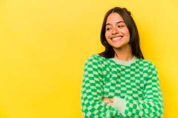 Young hispanic woman isolated on yellow background smiling confident with crossed arms.