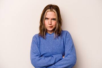 Young caucasian woman isolated on white background frowning face in displeasure, keeps arms folded.