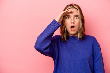 Young caucasian woman isolated on pink background shouts loud, keeps eyes opened and hands tense.