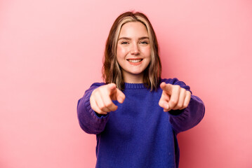Young caucasian woman isolated on pink background cheerful smiles pointing to front.