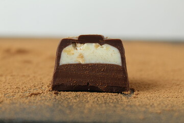 body chocolate candy with chocolate and white milk cream filling close-up against the cocoa background. A day of chocolate sweets without diet. handmade sweets
