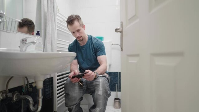 Open door to bathroom with man play video game on smartphone 4K