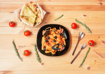 Pappardelle pasta with seafood with tomato sauce and focaccia bread. Top view.