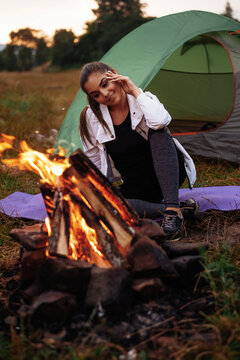 The girl is warming herself by the fire, smiling and looking to the fire