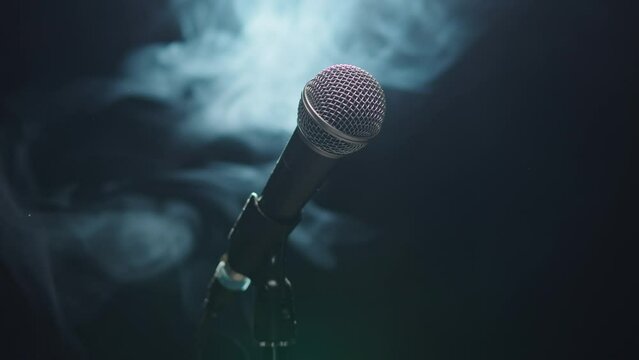 Microphone close-up, mic with smoke and black background. Karaoke singing, nightlife club or bar. Music, musical concert.