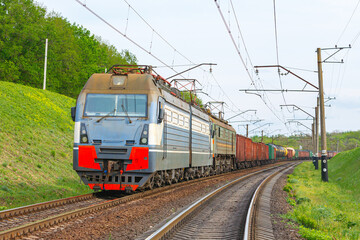 Fototapeta na wymiar Four powerful electric locomotives pull a long heavy train to the sorting station. Spring evening lighting.
