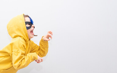 A 6-year-old girl emotionally imitates a cat, emotions on her face, hisses. Gray background and copy space.