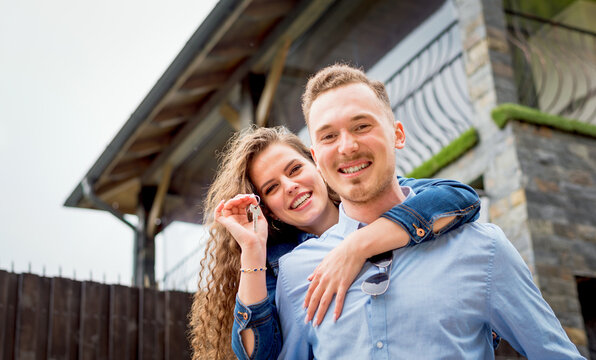 Portrait of smiling couple standing outside near their new house recently bought