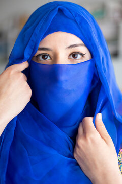 Portrait of young Muslim woman covering part of her face with characteristic Islamic veil. Close up shot.
