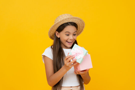 shocked teen kid hold present box on yellow background