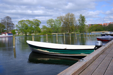 Naklejka na ściany i meble Landscape. Wooden embankment pier for boats on the lake. Place for walking in the city park.