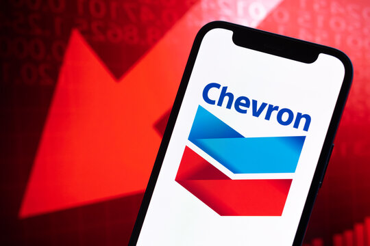 Chevron oil and gas prices, logo close-up. Collapse, petroleum crisis, red arrow down on stock market graphs background photo