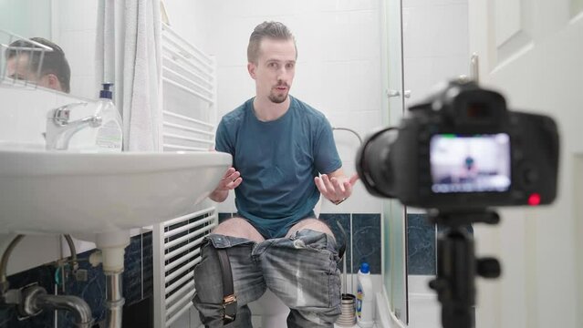 Influencer man in bathroom on toilet recording video talking about shit 4K