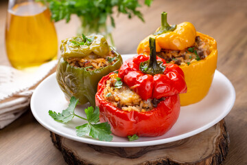 Stuffed peppers, halves of peppers stuffed with rice, dried tomatoes, herbs and cheese in a baking dish on a blue wooden table, top view. Vegetarian dish, stuffed vegetables