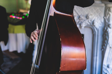 Concert view of contrabass violoncello player with vocalist and musical band during jazz orchestra band performing music, violoncellist cello jazz player on stage
