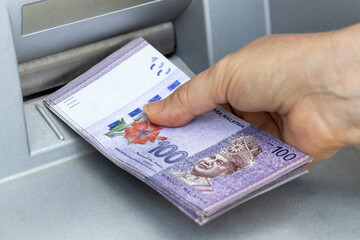 A woman chooses Malaysian ringgit from an ATM, The highest denomination, A lot of money, Economic and financial concept, Rising cost of living