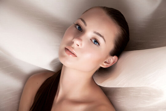 Beautiful Young Female Beauty Model with Fresh Makeup and Clean Hair with Studio Lighting against Beige Fabric. Nude Spa Beauty Concept