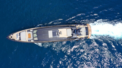 Aerial drone top down photo of luxury yacht with wooden deck cruising in deep blue sea of Mykonos...