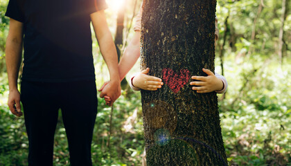 Nature lover family.Family embracing the tree with red heart. Concept of nature protection, care for environment. Environment day and earth day.