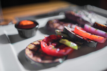 A plate of grilled beef meat with grilled slices of potatoes, tomatoes and onions