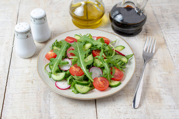 Spring vegan salad with spinach, cherry tomatoes, corn salad, baby spinach, cucumber and radish. Healthy food concept. Gray stone table. Top view. 