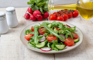 Spring vegan salad with spinach, cherry tomatoes, corn salad, baby spinach, cucumber and radish. Healthy food concept. wooden table. Top view. 