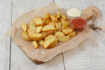 Baked potato wedges with sauces, tomato sauce and mayonnaise served on cutting board - homemade organic vegetable vegan vegetarian potato wedges snack, food meal