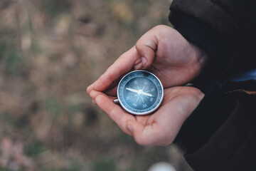 Navigation compass in hand. Travel and camping in forest. Finding path and direction
