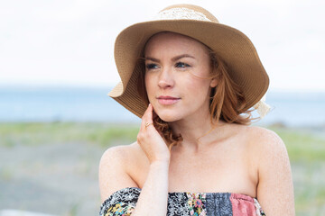 Pretty woman with red hair and freckles at the ocean beach