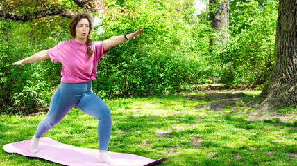 Young plump woman practicing yoga in green garden outdoor,breath hard, standing in Warrior two...