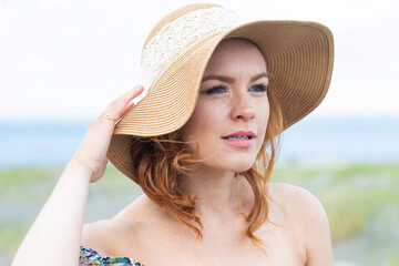 Pretty woman with red hair and freckles at the ocean beach