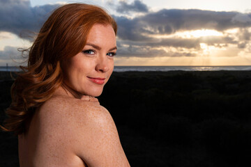 Pretty woman with red hair and freckles at the ocean beach